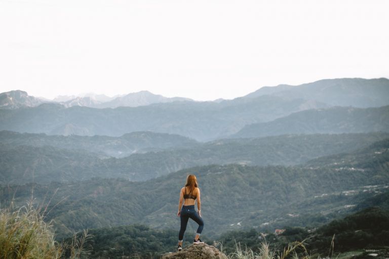 woman standing on cliff during daytime